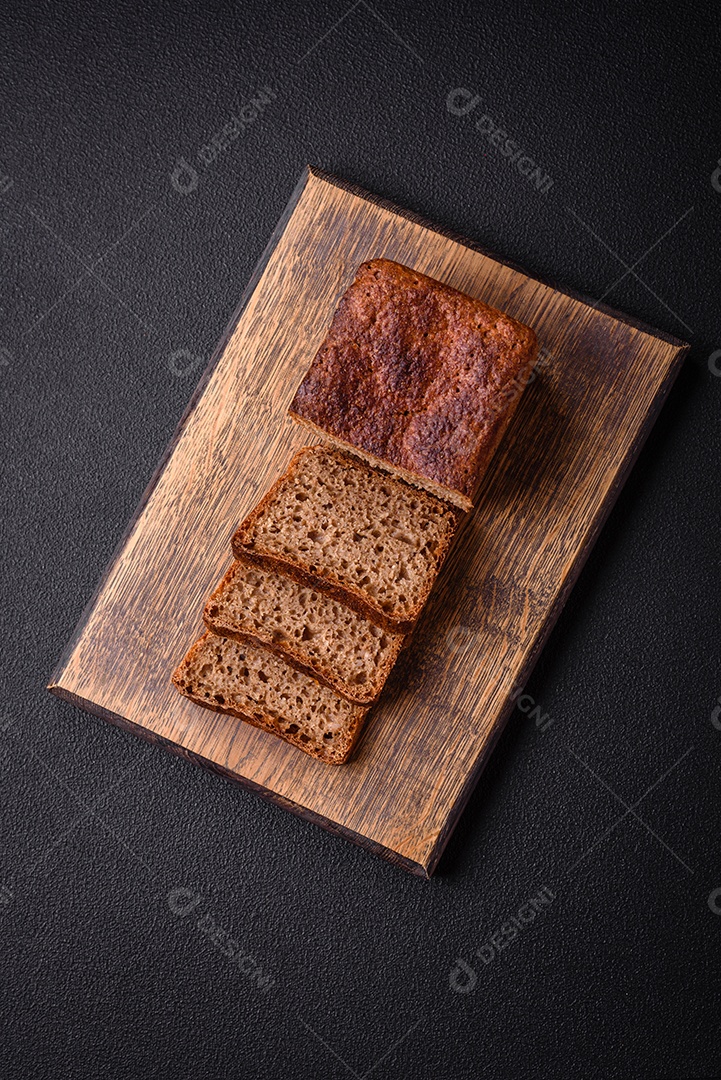 Delicioso pão integral crocante fresco com sementes e grãos sobre um fundo escuro de concreto