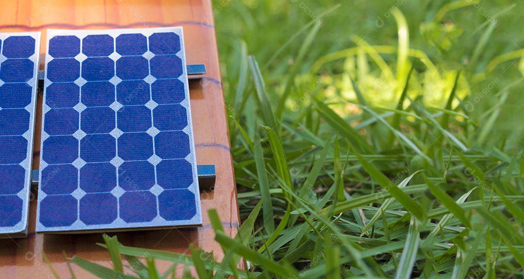 Painel solar fotovoltaico ao lado de um fio de tomada no fundo da grama