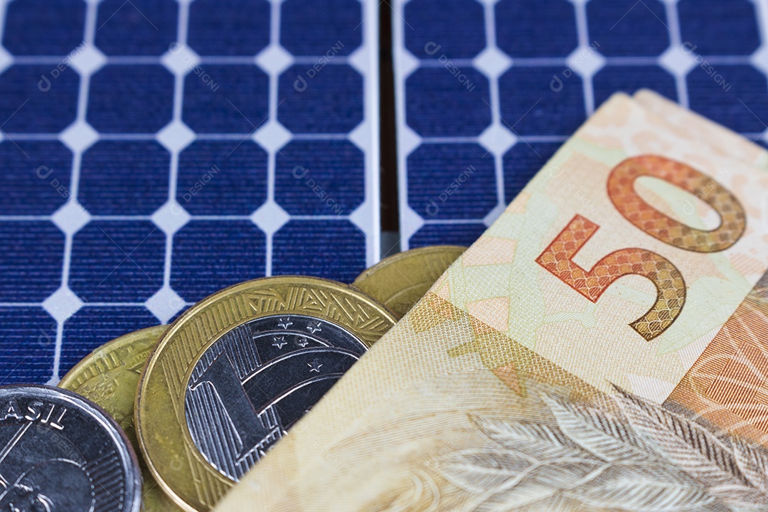 Dinheiro e painel de energia solar fotovoltaica brasileiro notas e moedas brasileiras em cima de um painel solar