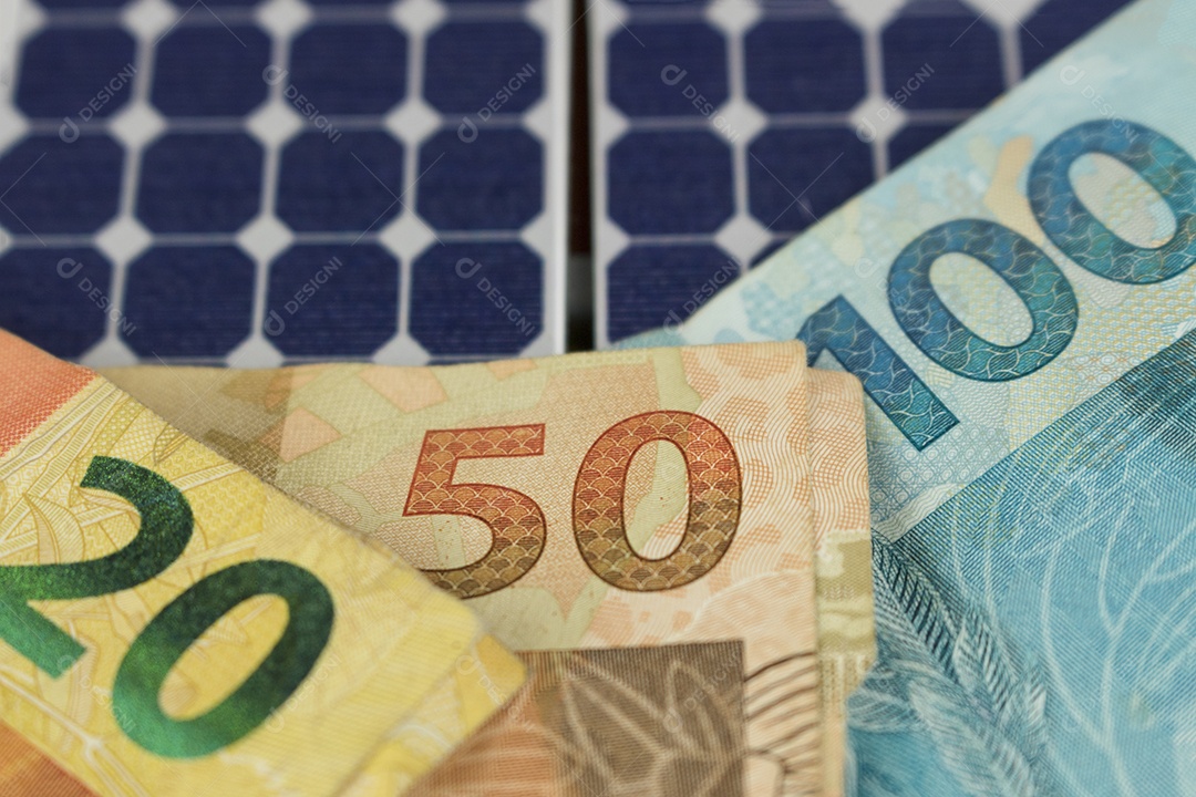 Dinheiro e painel de energia solar fotovoltaica brasileiro notas e moedas brasileiras em cima de um painel solar