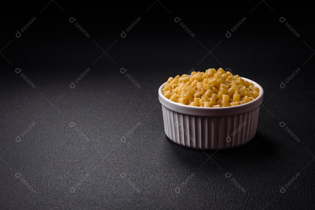 Deliciosa massa ditali de trigo duro com sal e especiarias sobre um fundo escuro de concreto