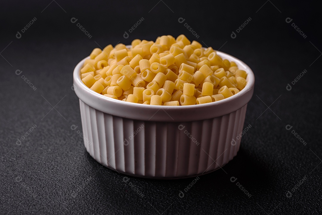 Deliciosa massa ditali de trigo duro com sal e especiarias sobre um fundo escuro de concreto