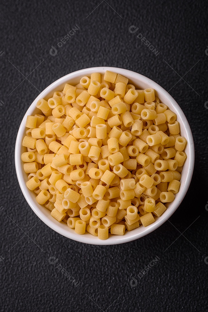 Deliciosa massa ditali de trigo duro com sal e especiarias sobre um fundo escuro de concreto