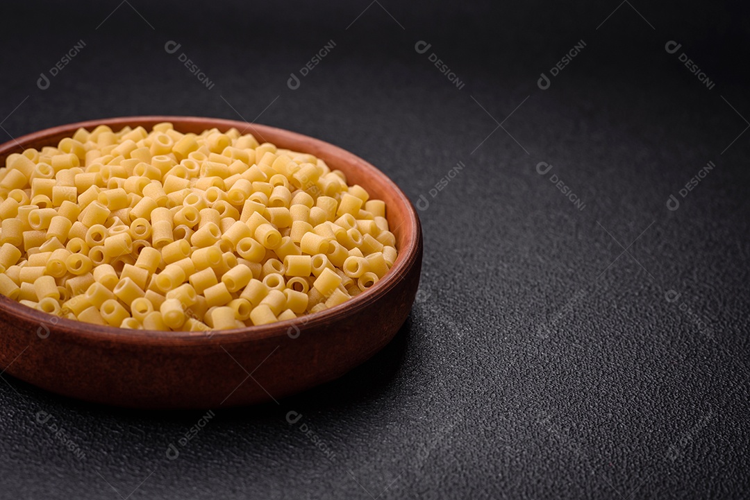 Deliciosa massa ditali de trigo duro com sal e especiarias sobre um fundo escuro de concreto