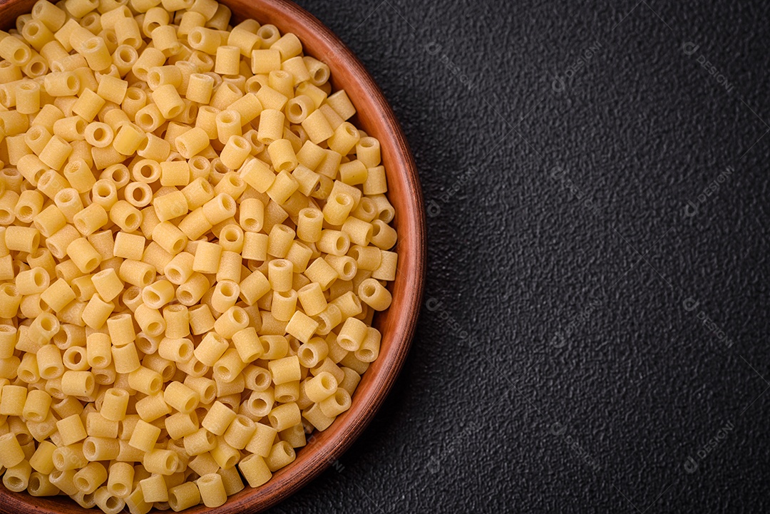 Deliciosa massa ditali de trigo duro com sal e especiarias sobre um fundo escuro de concreto