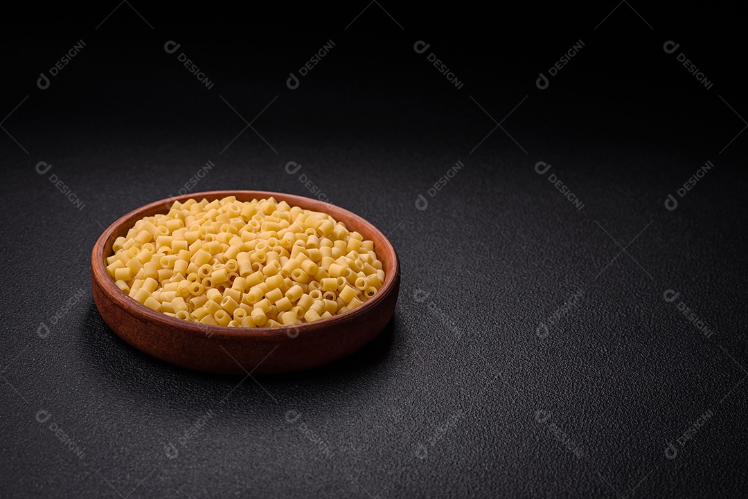 Deliciosa massa ditali de trigo duro com sal e especiarias sobre um fundo escuro de concreto