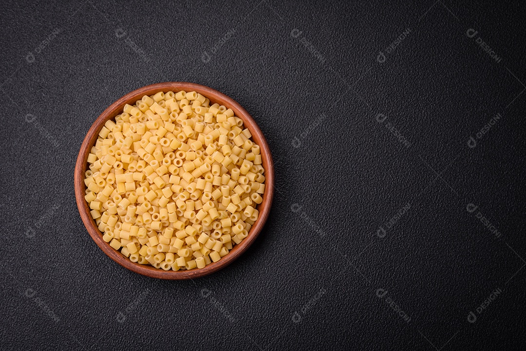 Deliciosa massa ditali de trigo duro com sal e especiarias sobre um fundo escuro de concreto