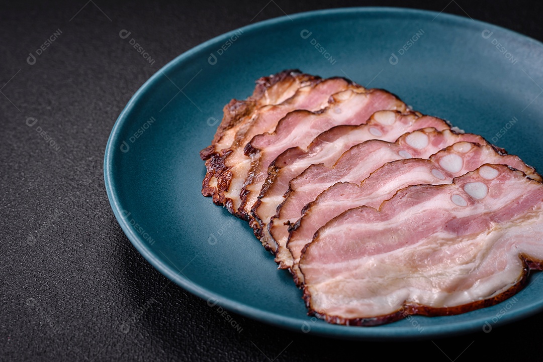 Deliciosa pancetta fresca ou bacon com sal e especiarias cortadas em fatias finas sobre um fundo escuro de concreto