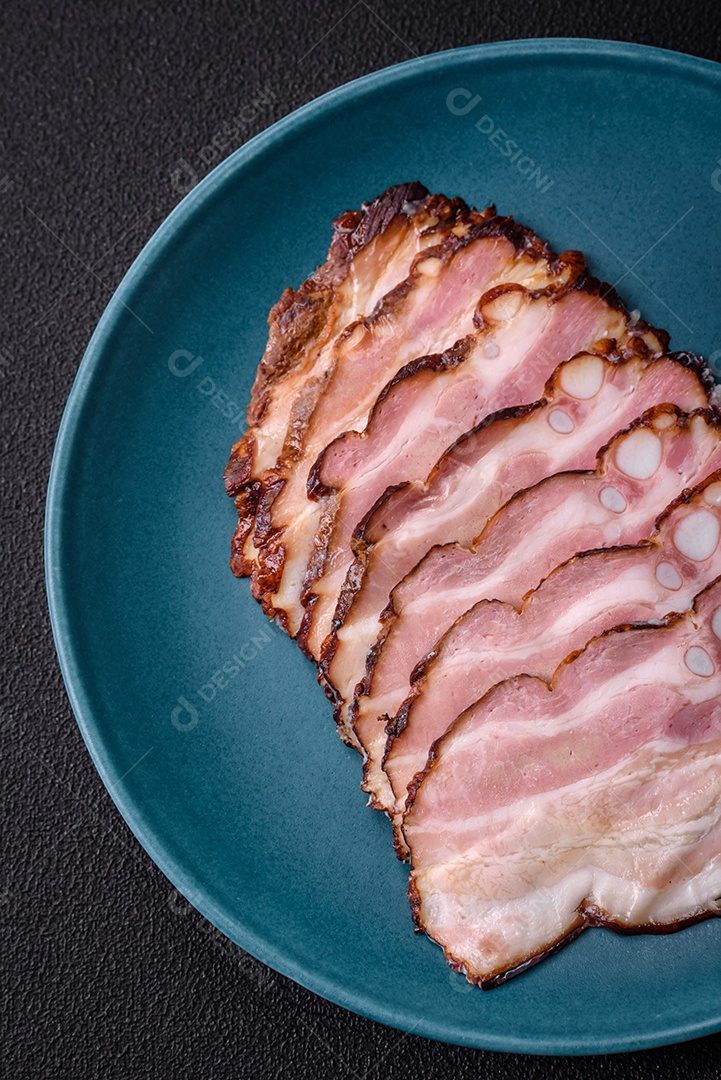 Deliciosa pancetta fresca ou bacon com sal e especiarias cortadas em fatias finas sobre um fundo escuro de concreto