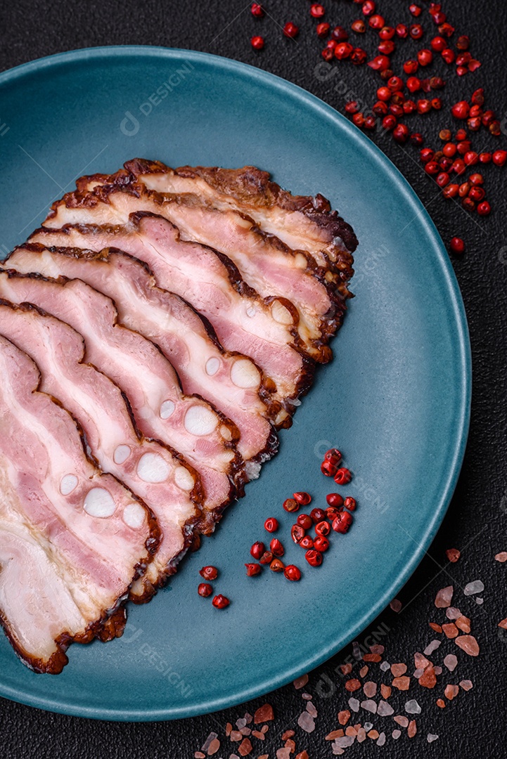 Deliciosa pancetta fresca ou bacon com sal e especiarias cortadas em fatias finas sobre um fundo escuro de concreto
