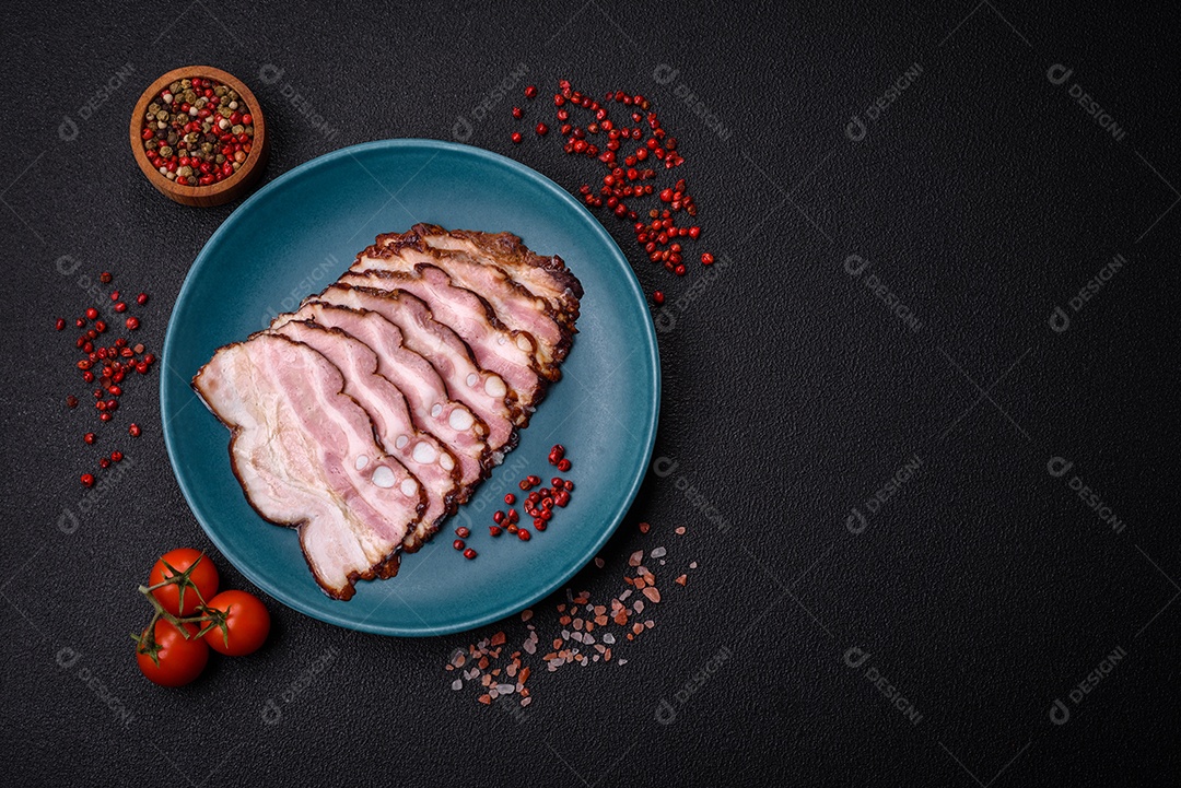 Deliciosa pancetta fresca ou bacon com sal e especiarias cortadas em fatias finas sobre um fundo escuro de concreto