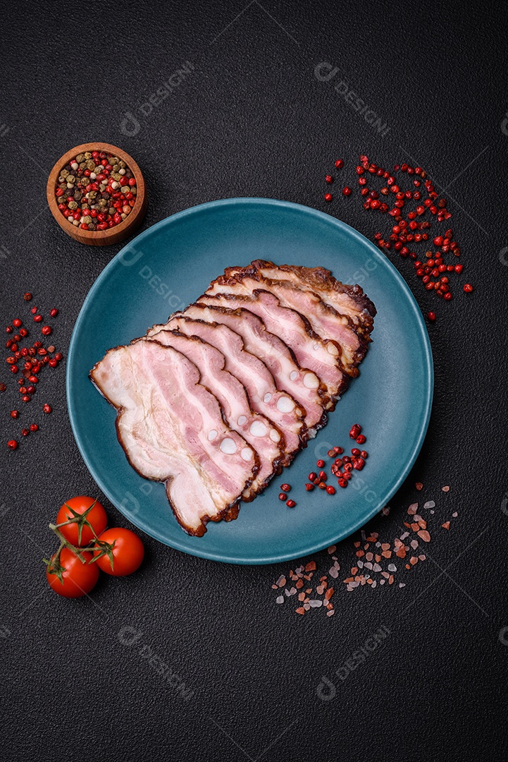 Deliciosa pancetta fresca ou bacon com sal e especiarias cortadas em fatias finas sobre um fundo escuro de concreto