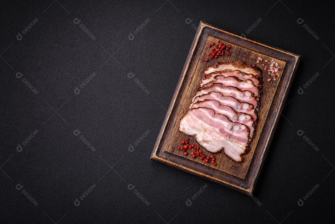 Deliciosa pancetta fresca ou bacon com sal e especiarias cortadas em fatias finas sobre um fundo escuro de concreto