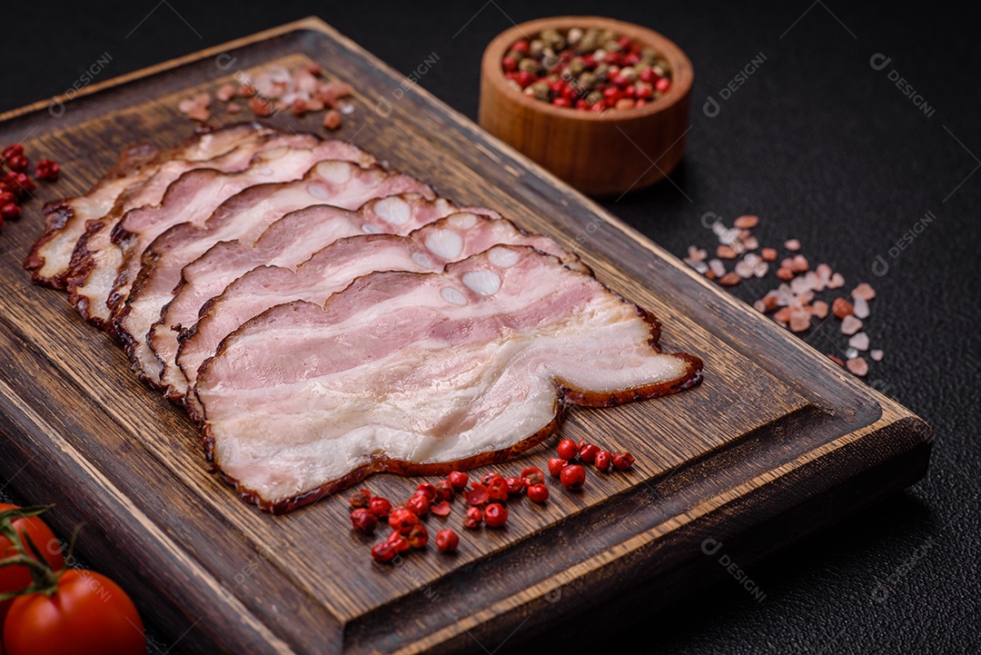 Deliciosa pancetta fresca ou bacon com sal e especiarias cortadas em fatias finas sobre um fundo escuro de concreto