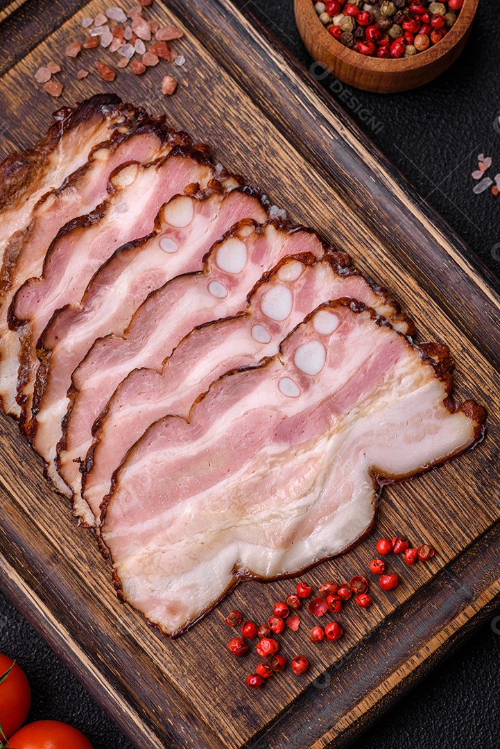 Deliciosa pancetta fresca ou bacon com sal e especiarias cortadas em fatias finas sobre um fundo escuro de concreto