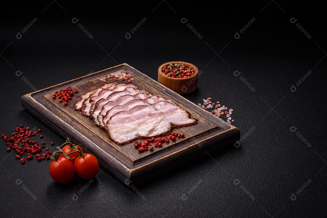 Deliciosa pancetta fresca ou bacon com sal e especiarias cortadas em fatias finas sobre um fundo escuro de concreto