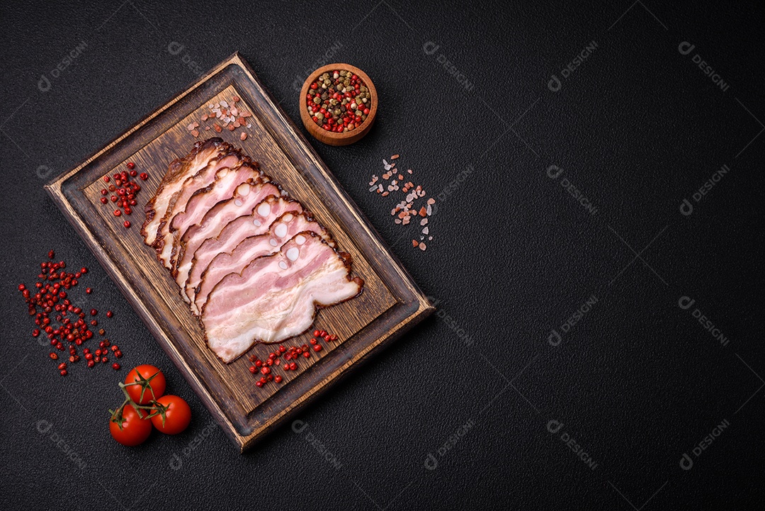 Deliciosa pancetta fresca ou bacon com sal e especiarias cortadas em fatias finas sobre um fundo escuro de concreto