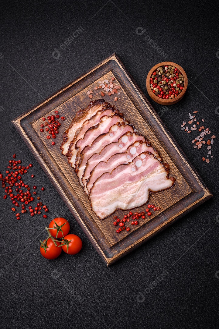 Deliciosa pancetta fresca ou bacon com sal e especiarias cortadas em fatias finas sobre um fundo escuro de concreto