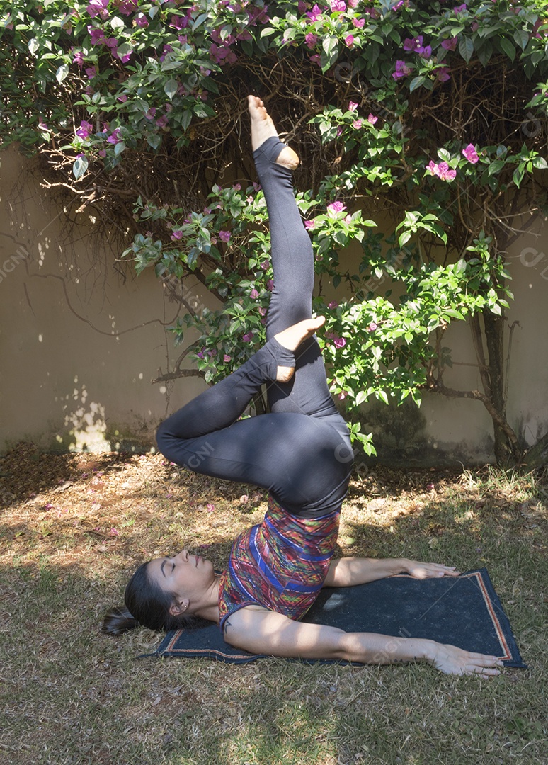 Jovem brasileira praticando ioga no jardim da casa com sol e flores Imagem conceitual de ioga