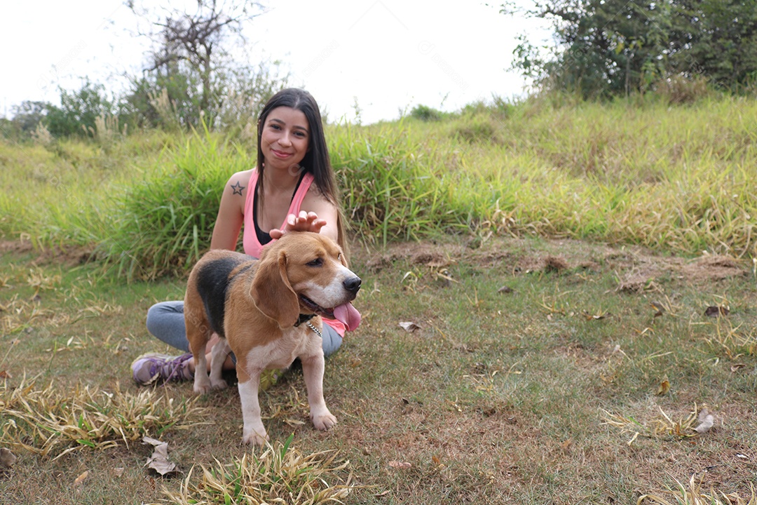 Adolescente morena com cachorro beagle no parque ao ar livre