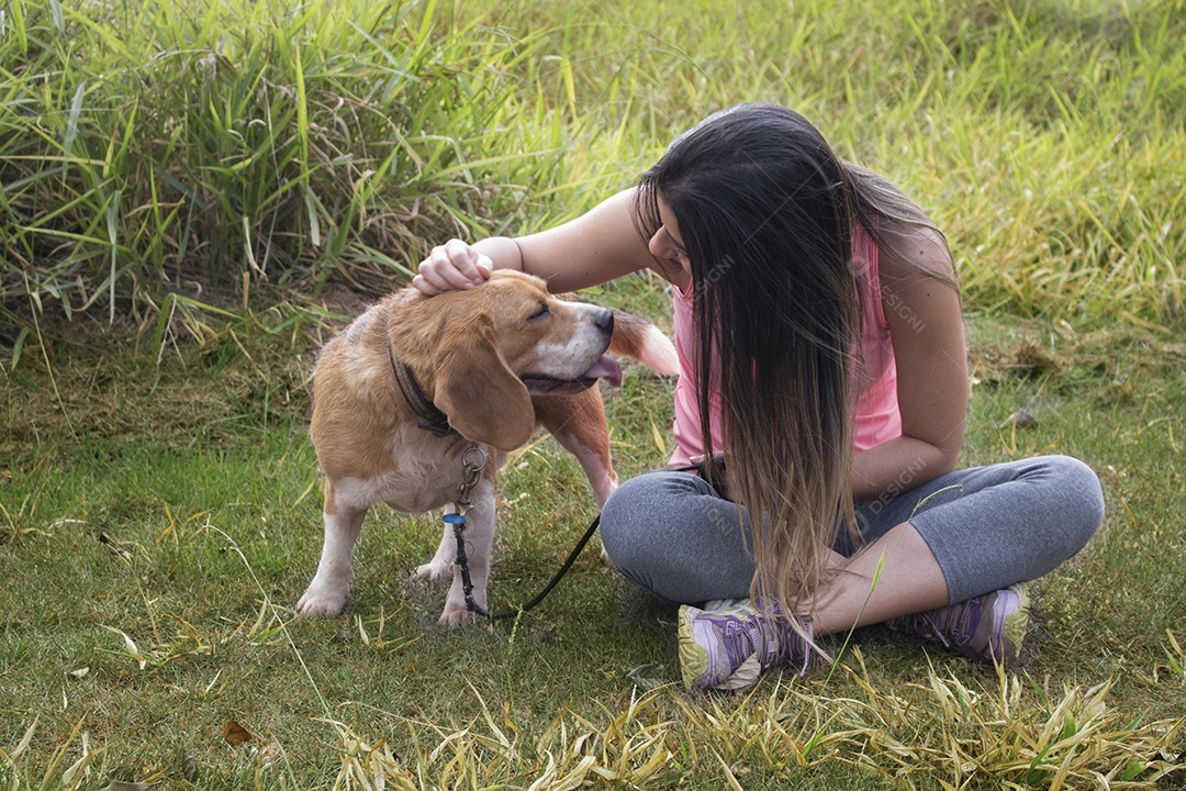 Adolescente morena com cachorro beagle no parque ao ar livre