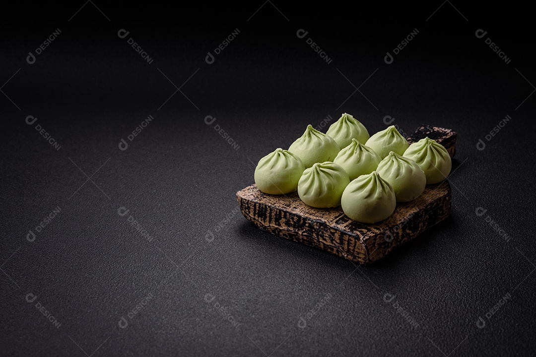 Khinkali cru ou bolinhos verdes com sal, especiarias e ervas sobre um fundo escuro de concreto