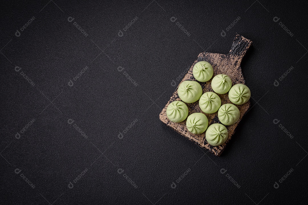 Khinkali cru ou bolinhos verdes com sal, especiarias e ervas sobre um fundo escuro de concreto