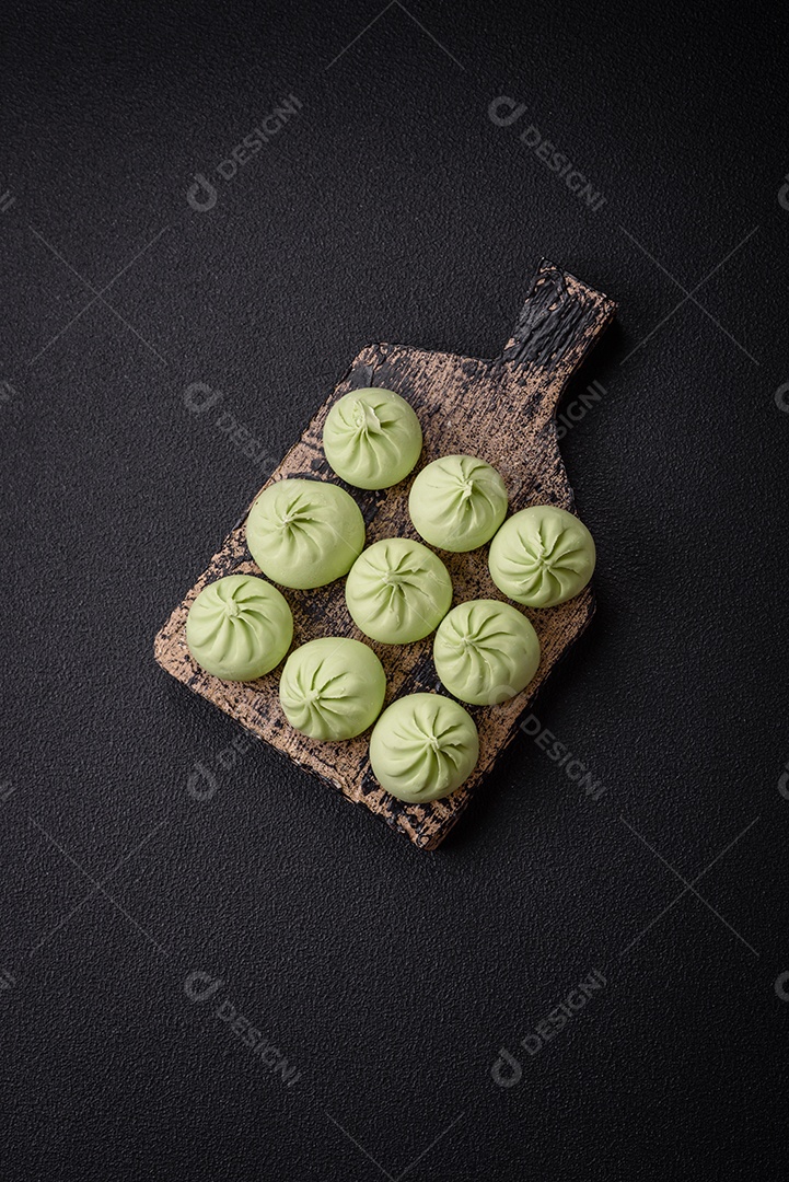 Khinkali cru ou bolinhos verdes com sal, especiarias e ervas sobre um fundo escuro de concreto