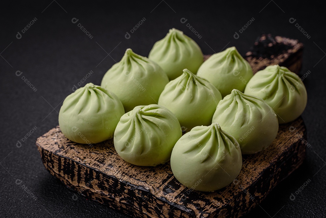 Khinkali cru ou bolinhos verdes com sal, especiarias e ervas sobre um fundo escuro de concreto