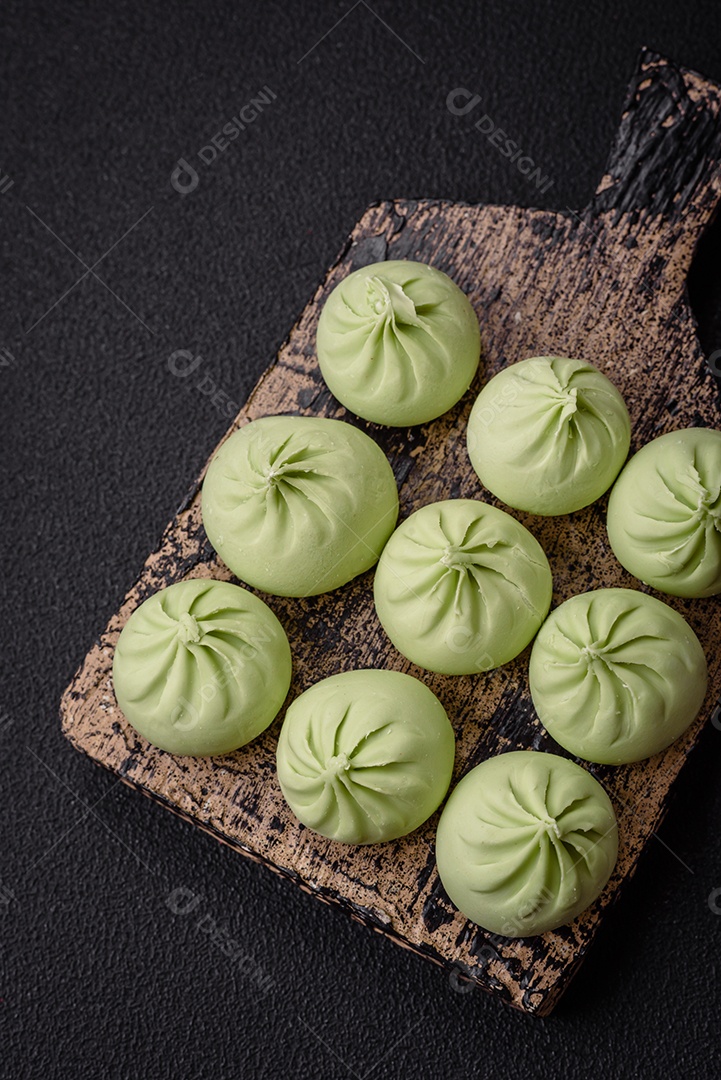 Khinkali cru ou bolinhos verdes com sal, especiarias e ervas sobre um fundo escuro de concreto