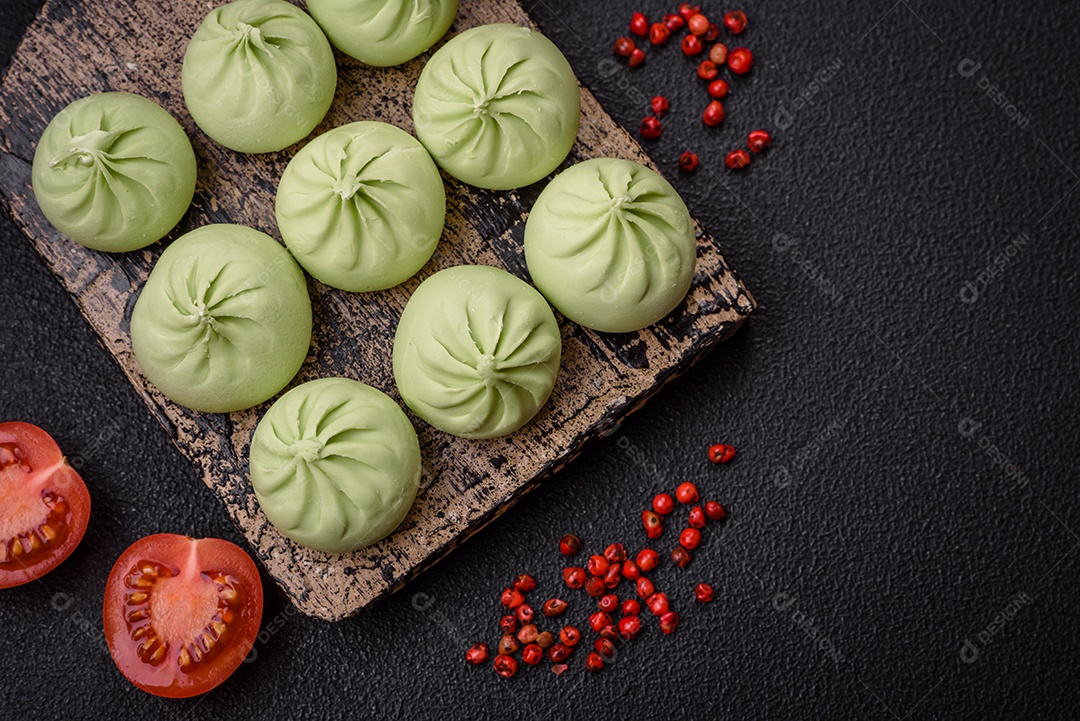 Khinkali cru ou bolinhos verdes com sal, especiarias e ervas sobre um fundo escuro de concreto