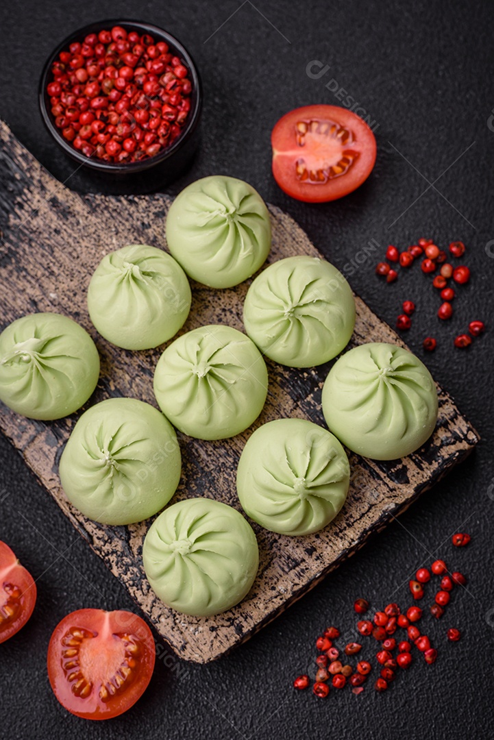 Khinkali cru ou bolinhos verdes com sal, especiarias e ervas sobre um fundo escuro de concreto