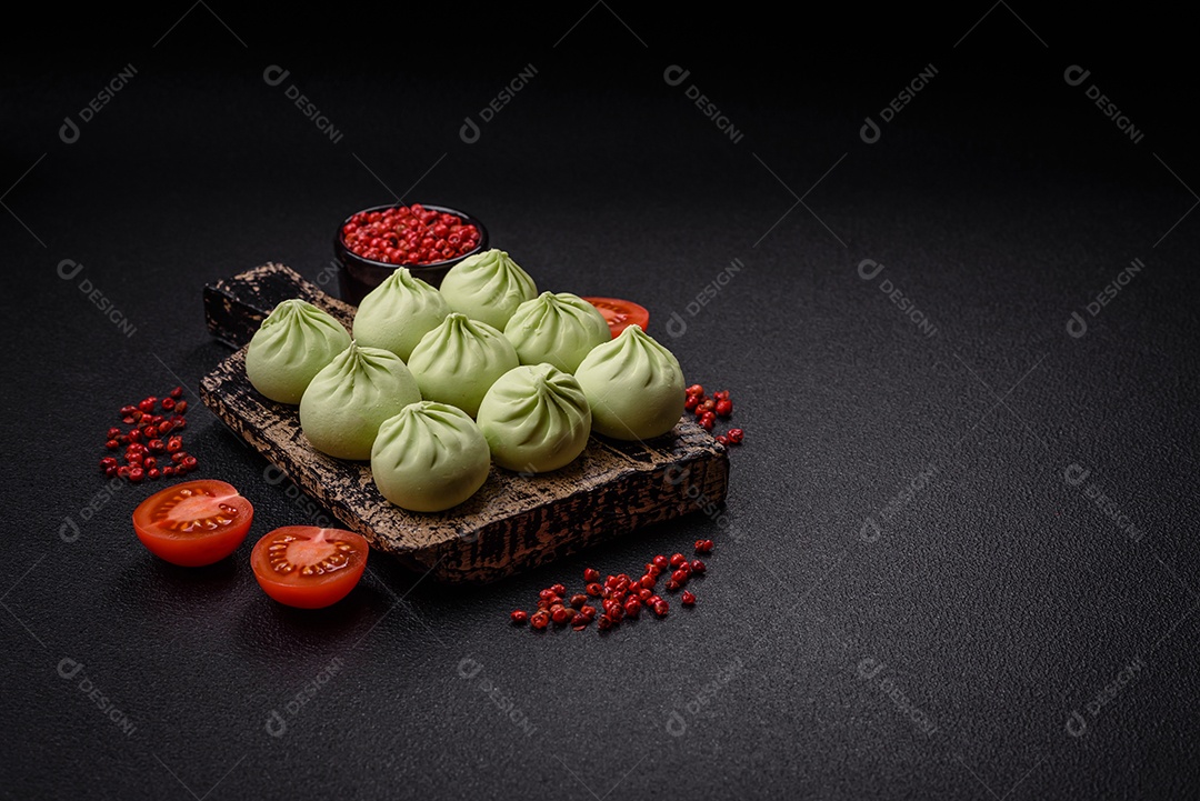 Khinkali cru ou bolinhos verdes com sal, especiarias e ervas sobre um fundo escuro de concreto