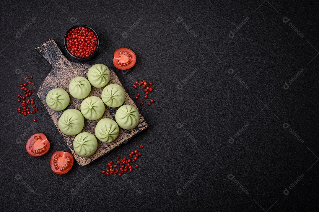 Khinkali cru ou bolinhos verdes com sal, especiarias e ervas sobre um fundo escuro de concreto