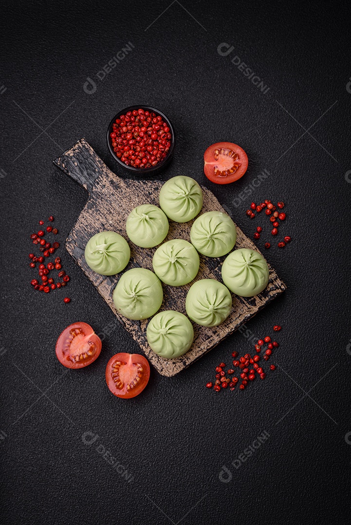 Khinkali cru ou bolinhos verdes com sal, especiarias e ervas sobre um fundo escuro de concreto