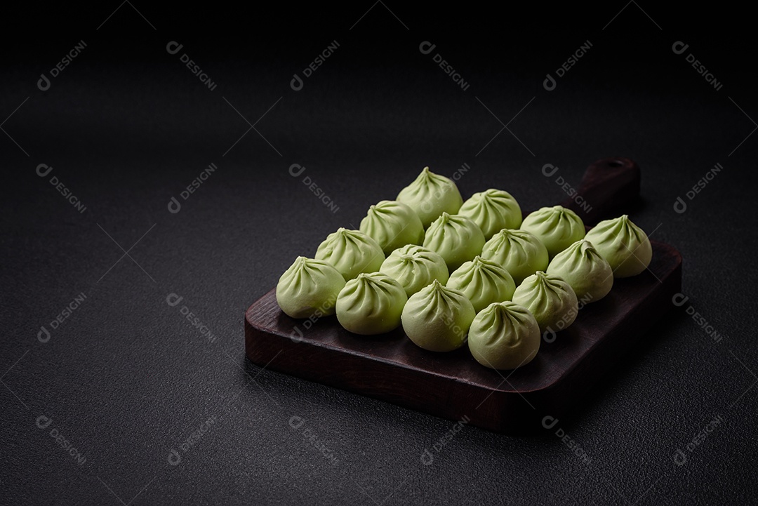 Khinkali cru ou bolinhos verdes com sal, especiarias e ervas sobre um fundo escuro de concreto