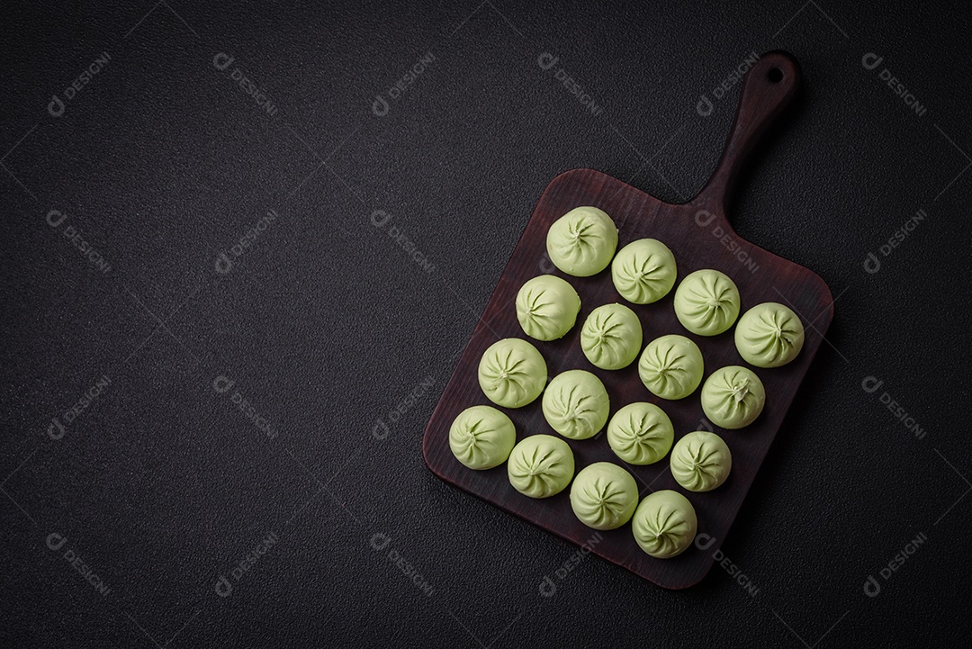 Khinkali cru ou bolinhos verdes com sal, especiarias e ervas sobre um fundo escuro de concreto