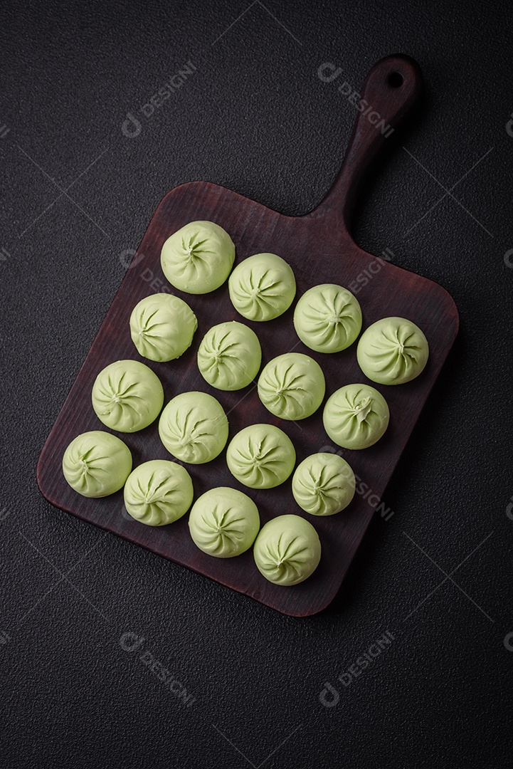 Khinkali cru ou bolinhos verdes com sal, especiarias e ervas sobre um fundo escuro de concreto