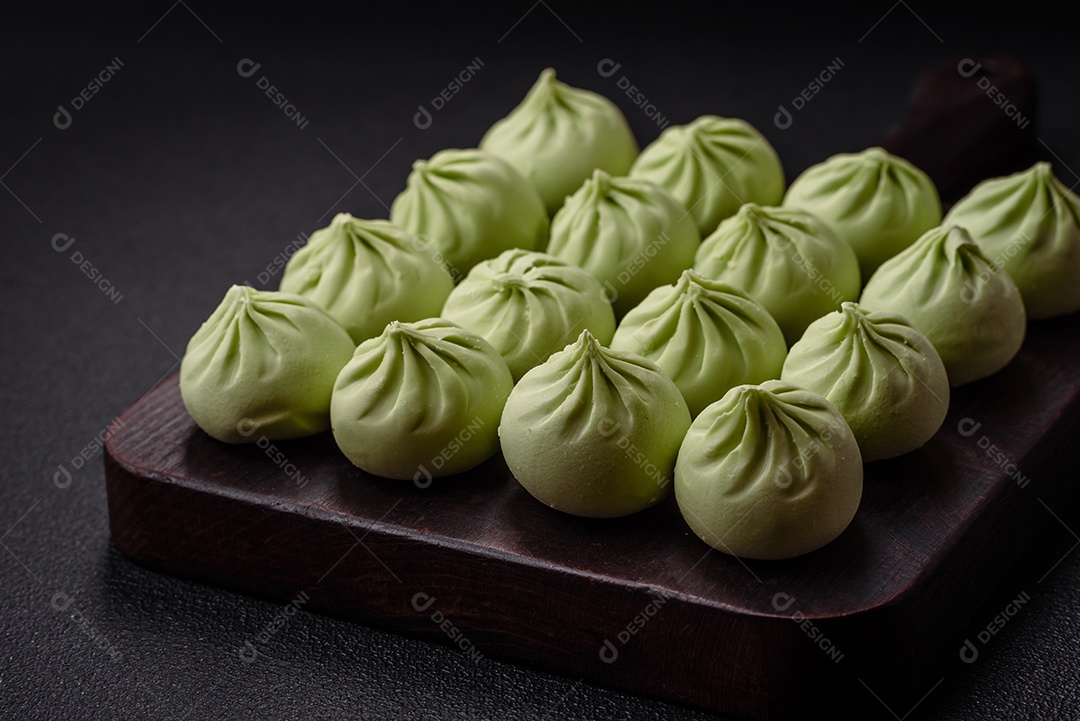 Khinkali cru ou bolinhos verdes com sal, especiarias e ervas sobre um fundo escuro de concreto