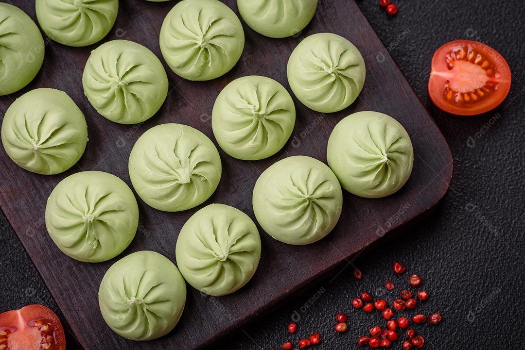 Khinkali cru ou bolinhos verdes com sal, especiarias e ervas sobre um fundo escuro de concreto