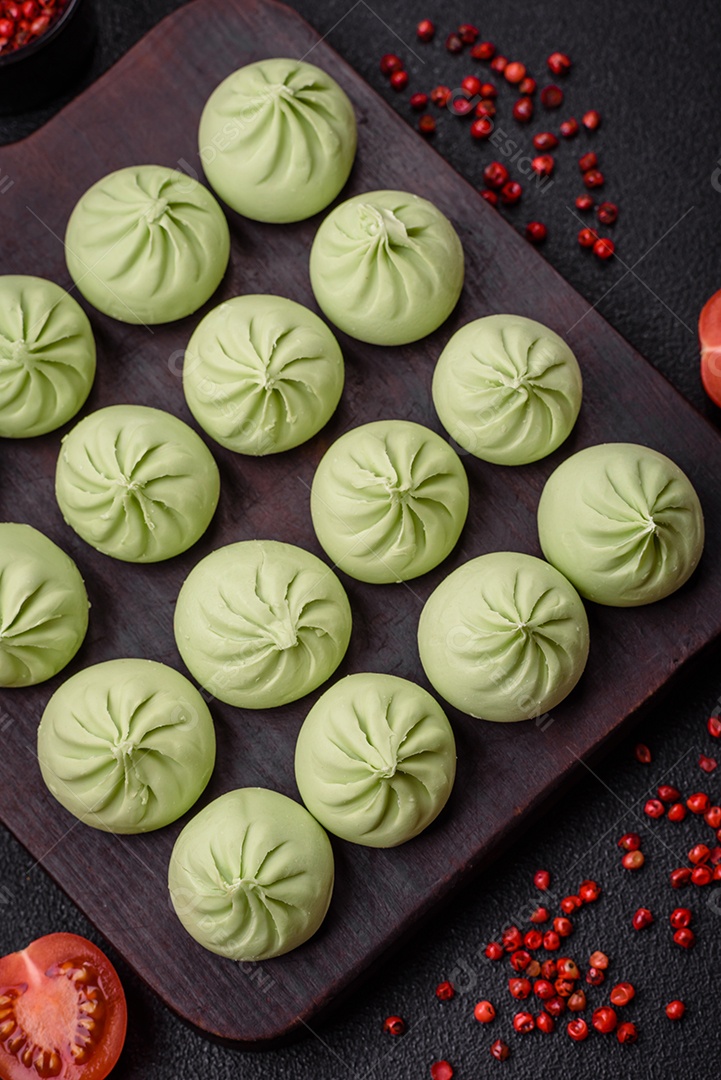 Khinkali cru ou bolinhos verdes com sal, especiarias e ervas sobre um fundo escuro de concreto