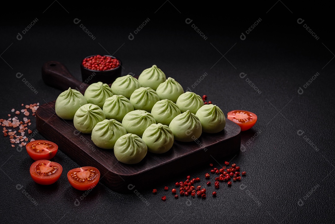 Khinkali cru ou bolinhos verdes com sal, especiarias e ervas sobre um fundo escuro de concreto