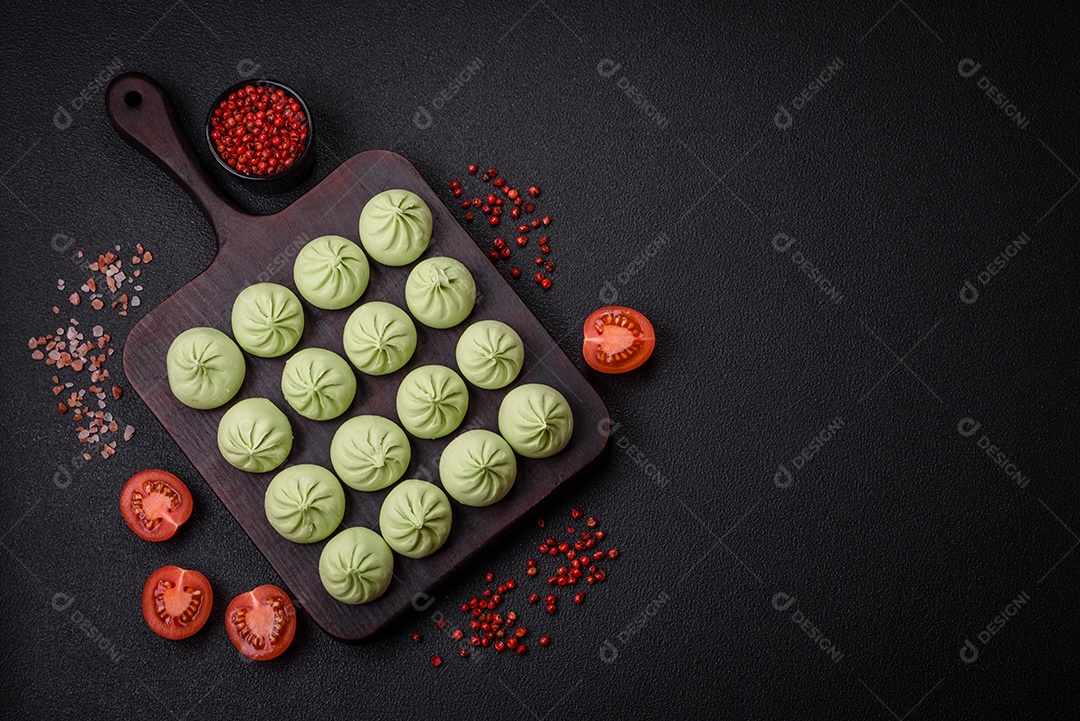 Khinkali cru ou bolinhos verdes com sal, especiarias e ervas sobre um fundo escuro de concreto