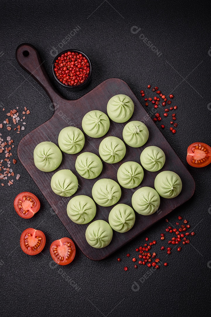 Khinkali cru ou bolinhos verdes com sal, especiarias e ervas sobre um fundo escuro de concreto