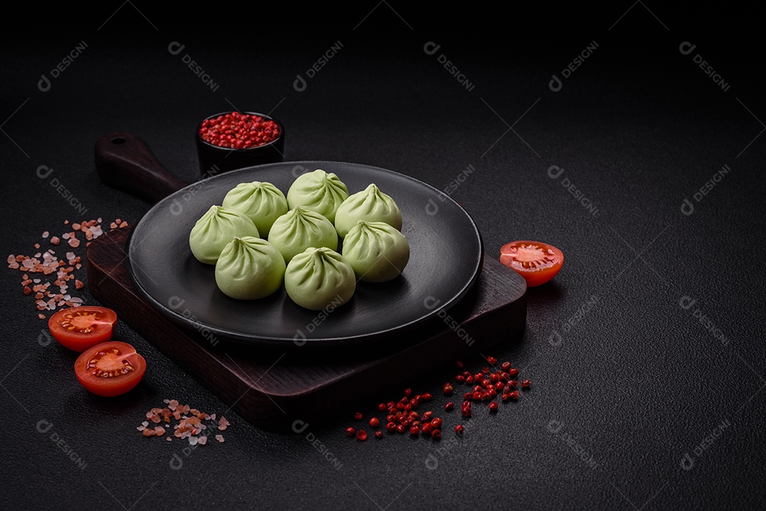 Khinkali cru ou bolinhos verdes com sal, especiarias e ervas sobre um fundo escuro de concreto