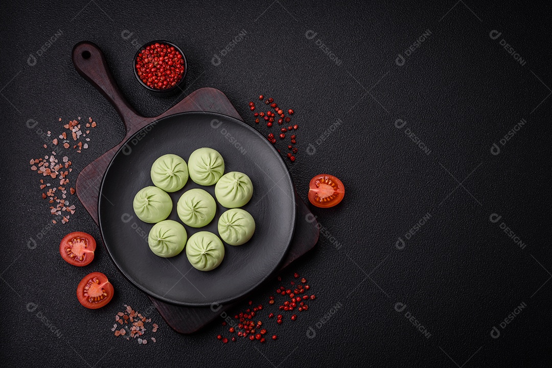 Khinkali cru ou bolinhos verdes com sal, especiarias e ervas sobre um fundo escuro de concreto