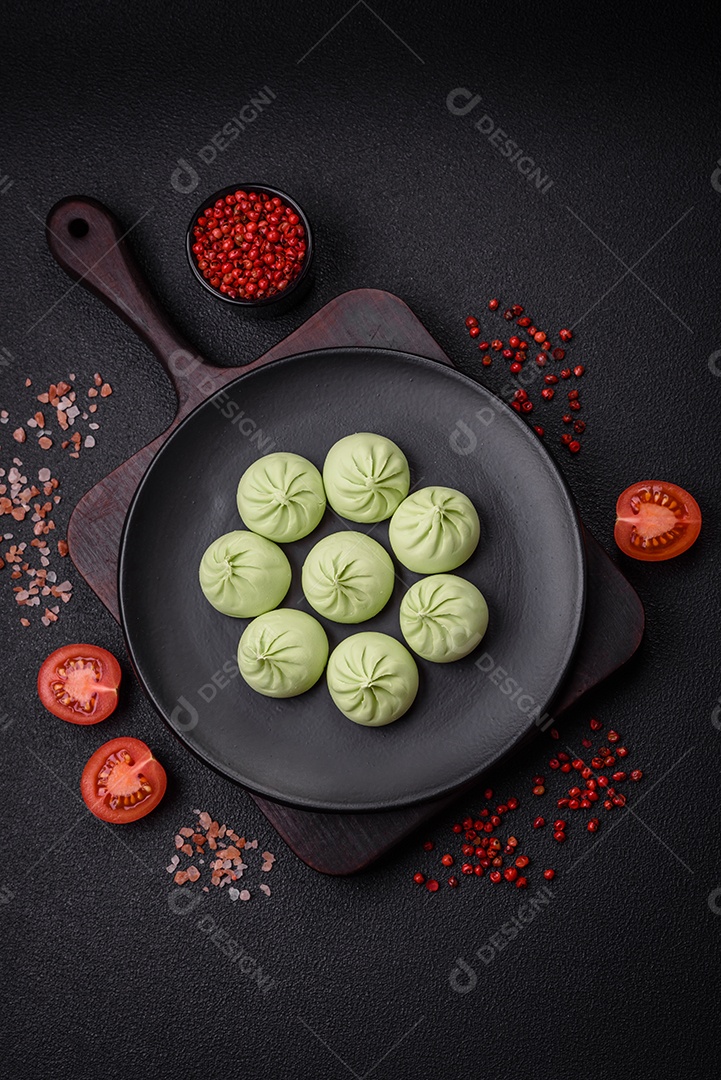 Khinkali cru ou bolinhos verdes com sal, especiarias e ervas sobre um fundo escuro de concreto