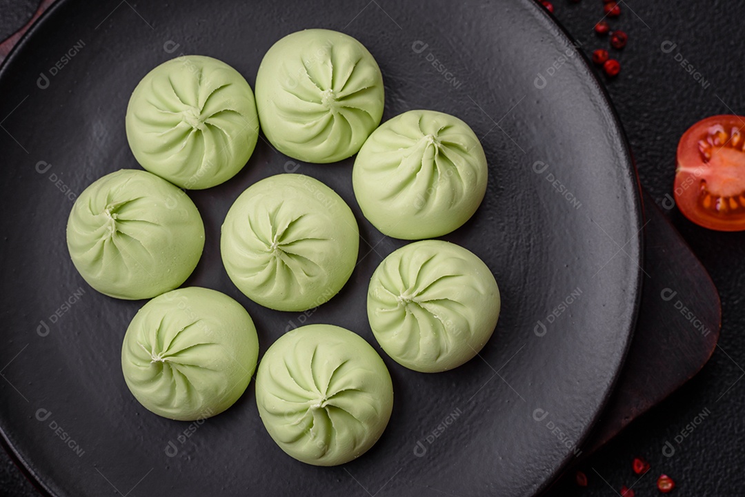 Khinkali cru ou bolinhos verdes com sal, especiarias e ervas sobre um fundo escuro de concreto