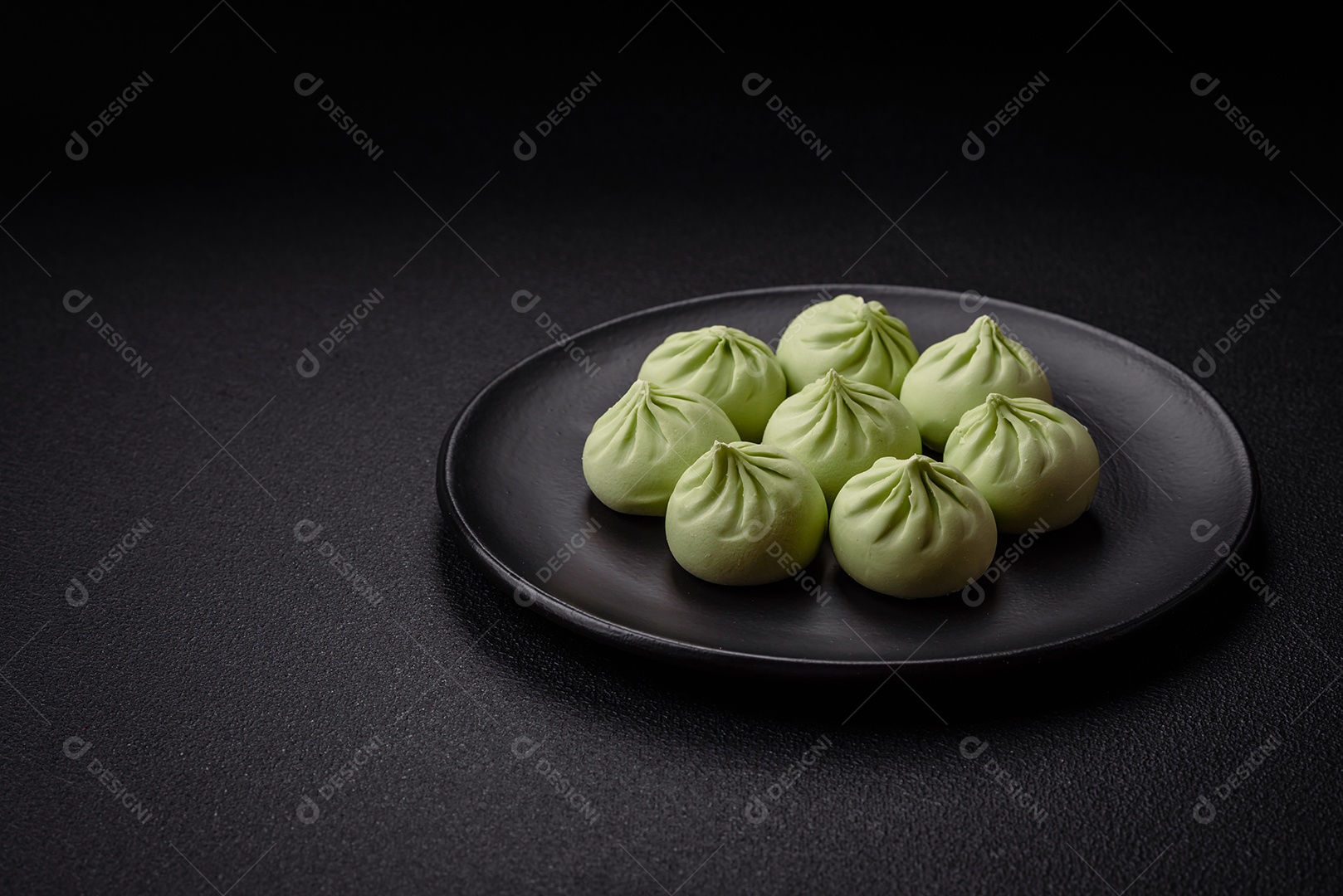 Khinkali cru ou bolinhos verdes com sal, especiarias e ervas sobre um fundo escuro de concreto