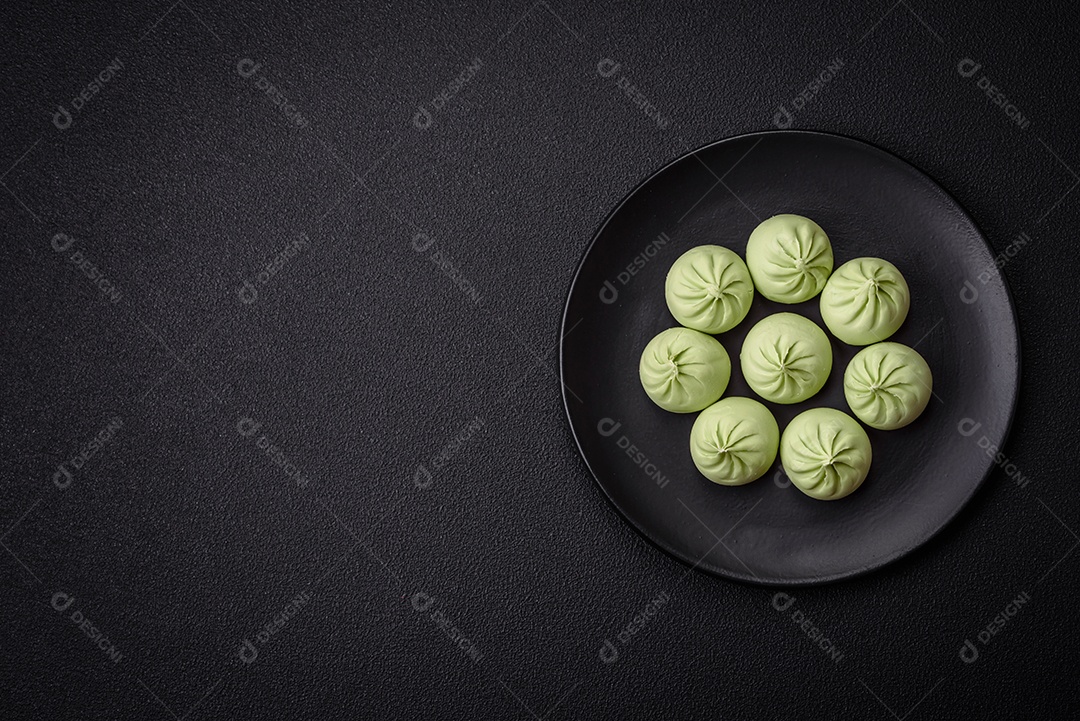 Khinkali cru ou bolinhos verdes com sal, especiarias e ervas sobre um fundo escuro de concreto